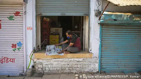 A shopkeeper reads the newspaper at his shop during lockdown in wake of Coronavirus pandemic in Prayagraj, Uttar Pradesh, India