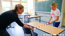 Nicola Witzlau and Claudia Mohme prepare a classroom at the Freiherr von Stein school for a re-opening, as the spread of coronavirus disease (COVID-19) continues in Bonn, Germany, April 20, 2020. REUTERS/Wolfgang Rattay