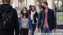 LEIPZIG, GERMANY - APRIL 20: People, including a couple wearing protective face masks who said they did not mind being photographed, walk in the city center among shops open for the first time since March on the first day of the easing of some restrictions during the coronavirus crisis on April 20, 2020 in Leipzig, Germany. Across Germany today many states, but not all, are introducing steps to lift restrictions that have had a deep economic and social impact, including the reopening of smaller-size stores, allowing high school students to take exams and restarting production lines in some factories. The number of Covid-19 infections is continuing to rise, but at a slower rate than in previous weeks, which is giving the federal and state governments hope that the time is right to begin lifting restrictions. (Photo by Sean Gallup/Getty Images)