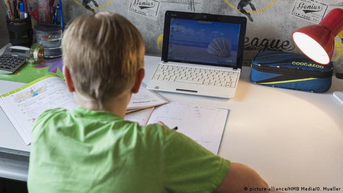 Ein Junge sitzt am Schreibtisch, vor ihm ein Mathebuch, ein Heft und ein Laptop.
