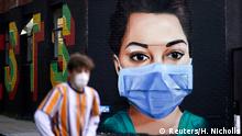 A man wearing a protective mask walks past a mural depicting a nurse in Shoreditch, amid the coronavirus disease (COVID-19) outbreak, in London, Britain April 21, 2020. REUTERS/Henry Nicholls TPX IMAGES OF THE DAY