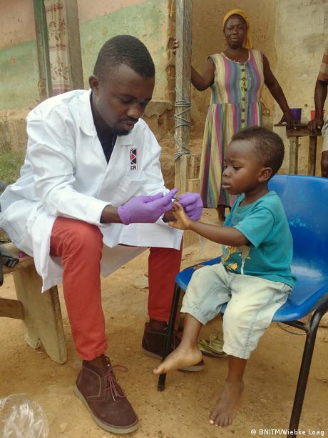 Ein Arzt untersucht ein Kind auf Malaria-Parasiten.