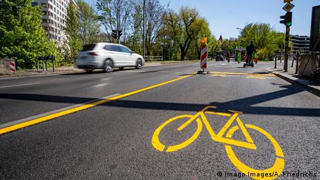 A image of a road with a temporary cycle path and an image of a bike painted in yellow.