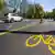 A image of a road with a temporary cycle path and an image of a bike painted in yellow.