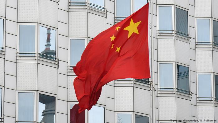 The Chinese flag flies in front of the embassy in Berlin, the TV tower on Alexanderplatz is reflected in the window