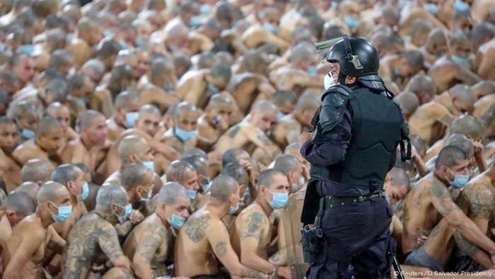 Cientos de presos en una cárcel de El Salvador, sentados en el suelo.