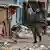 Soldado carrega caixas de ovos em uma rua com muito lixo