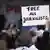 A person holding a sign that reads "Free all journalists"