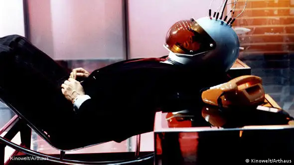 Mann liegend auf Stuhl mit Helm - Szene aus dem Film "Welt am Draht" von Rainer Werner Fassbinder