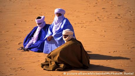 Drei Tuareg sitzen in langen Gewändern mit Kopfbedeckungen und Gesichtsschleiern auf Sand (picture-alliance/blickwinkel/McPhoto/M. Runkel)