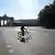 Samotny rowerzysta na pustej drodze. W tle Brama Brandenburska