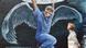 A male nurse is depicted on the side of a building wearing angel-like wings. A male nurse is depicted on the side of a building wearing angel-like wings.