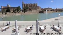 11.05.2020, Spanien, Palma: Ein Mann sitzt im Außenbereich einer Bar im Parc de la Mar. Im Hintergrund ist die Kathedrale von Palma zu sehen. Ab Montag dürfen in der «Phase 1» der Lockerungen der Corona-Maßnahmen unter anderem Bars, Restaurants, Geschäfte, Bibliotheken und religiöse Kultstätten wieder eröffnen. Foto: Clara Margais/dpa +++ dpa-Bildfunk +++ | Verwendung weltweit
