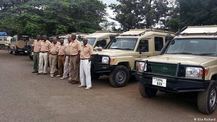 Tour guides wait for clients in Tanzania in front of safari vehicles