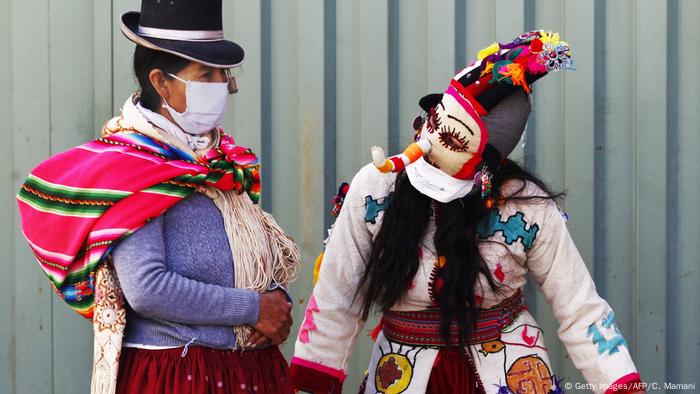 Una persona vestida de Kusillo, un arlequín tradicional de los Andes, recuerda en Perú a la gente usar mascarilla para cuidarse del coronavirus.