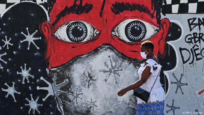 Una mujer de Costa de Marfil pasa frente a un muro grafiteado. 
