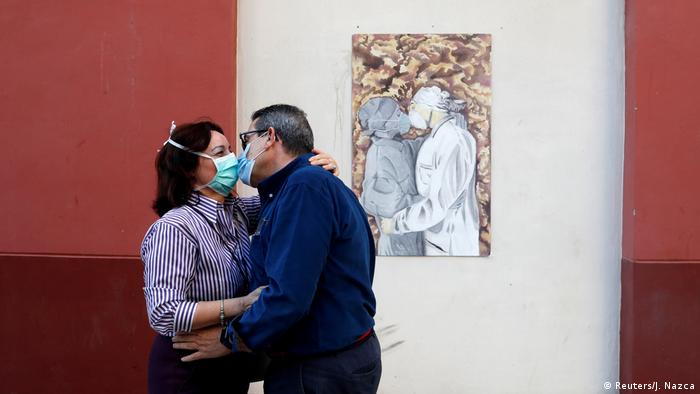 Una pareja de enfermeros españoles se besan junto a una pintura callejera. (18.05.2020).