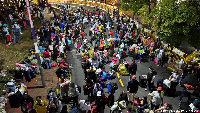 En la ciudad colombiana de Cali, migrantes venezolanos esperan con su equipaje a los autobuses que los llevarán de regreso a Venezuela.