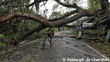 A man walks with his bicycle under an uprooted tree after Cyclone Amphan made its landfall, in South 24 Parganas district, in the eastern state of West Bengal, India, May 21, 2020. REUTERS/Rupak De Chowdhuri