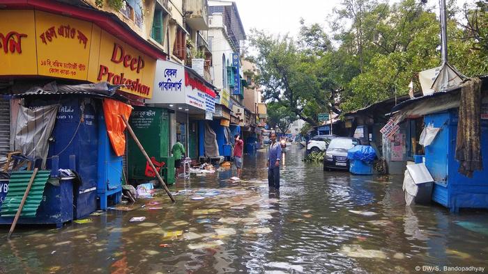 Pessoas andam em rua alagada em Bangladesh