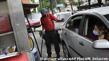 A worker wearing a face mask amid the new coronavirus pandemic works to fill up a client's gas tank at a PDVSA state oil company gas station in Caracas, Venezuela, Monday, May 25, 2020. The first of five tankers loaded with gasoline sent from Iran this week is expected to temporarily ease Venezuela's fuel crunch while defying Trump administration sanctions targeting the two U.S. foes. (AP Photo/Matias Delacroix) |