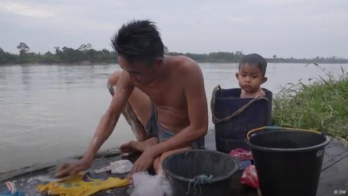 Un niño está dentro de un cubo de agua junto al río en Rukam, Indonesia
