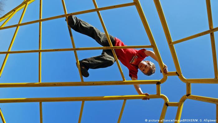 Deutschland Junge, 7 Jahre alt, turnt an einem Klettergerüst