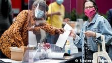 A poll worker wearing a mask to prevent the spread of coronavirus disease (COVID-19) gives a voter her ballot during the primary election voting in Philadelphia, Pennsylvania, U.S., June 2, 2020. REUTERS/Joshua Roberts