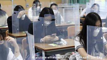 Школьники в масках и за перегородками в одной из школ в Южной Корее