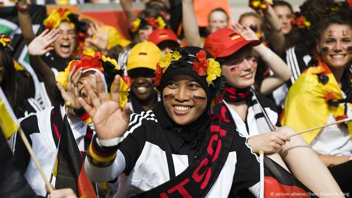 A girl in a headscarf cheers on Germany's handball team