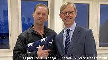 In this image provided by the U.S. State Department, Michael White holds an American flag as he poses for a photo with U,S, special envoy for Iran Brian Hook at the Zurich, Switzerland, airport after White’s release from Iran. White, a Navy veteran who's been detained in Iran for nearly two years has been released and is making his way home, with the first leg on a Swiss government aircraft. (U.S. State Department via AP) |
