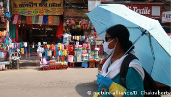 Женщина в медицинской маске и с зонтиком в Калькутте