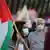 A protester in a face mask holding a Palestinian flag during a demonstration in Tel Aviv