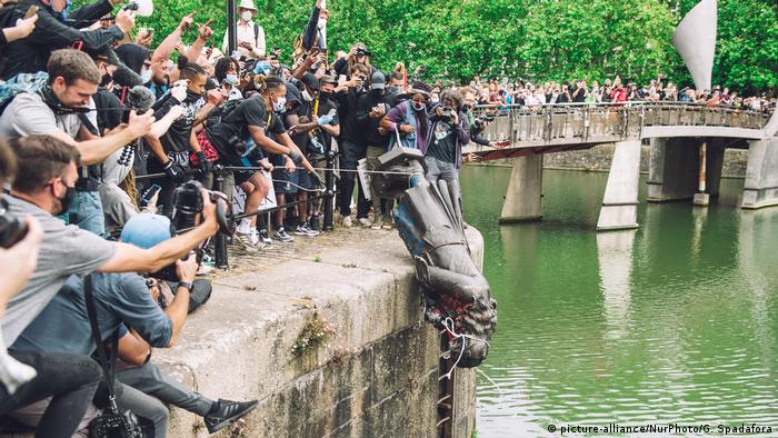 Foto kerumunan orang di jembatan dan tanggul sungai, beberapa memegang tali dan membiarkan patung turun ke air (picture-alliance/NurPhoto/G. Spadafora)