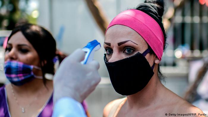 Un trabajador de salud toma la temperatura a una mujer, miembro de la comunidad LGBT en México.