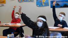 TOPSHOT - Schoolchildren wearing protective mouth masks and face shields attend a course in a classroom at Claude Debussy college in Angers, western France, on May 18, 2020 after France eased lockdown measures to curb the spread of the COVID-19 pandemic, caused by the novel coronavirus. (Photo by Damien MEYER / AFP) (Photo by DAMIEN MEYER/AFP via Getty Images)