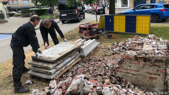 Workers clean up the site where the oldest statue of King Leopold II in Belgium was removed Tuesday. 