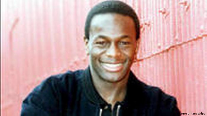 Justin Fashanu, of Nigerian descent, smiles at the camera while wearing a black shirt.