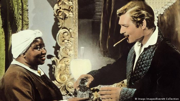 Filmstill Vom Winde verweht - ein weißer Darsteller mit Zigarillo schenkt einer schwarzen Darstellerin ein Getränk ein (Imago Images/Everett Collection)