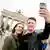 Zwei Touristen machen auf Selfie vorm Brandenburger Tor, der Vorplatz ist fast menschenleer (Foto: picture-alliance/dpa/K. Nietfeld).