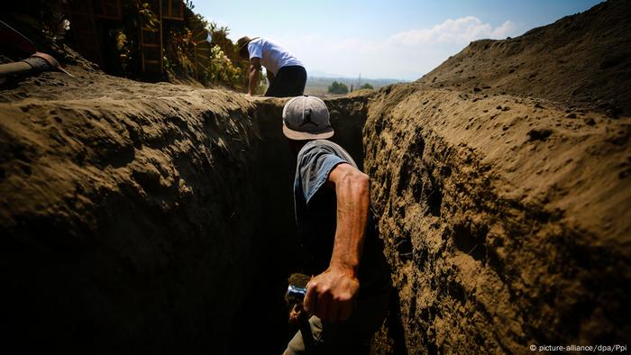 Un hombre de espaldas cava una fosa buscando restos de personas desaparecidas en Guadalajara, Mëxico.