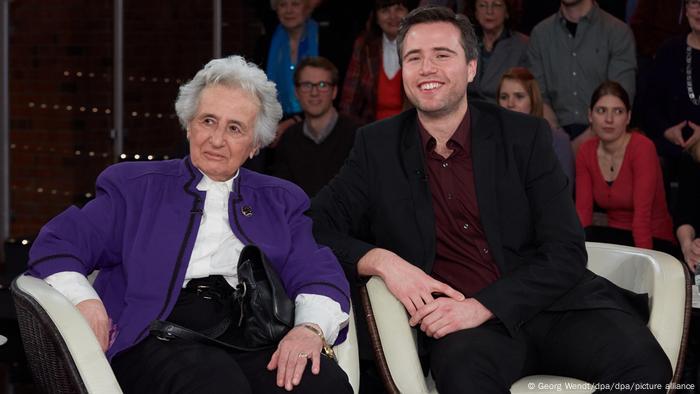 Anita Lasker-Wallfisch and her grandson seated in chairs looking toward the camera (picture-alliance/dpa/G. Wendt)