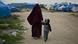 A Syrian woman holds her child's hand as they walk through a refugee camp in northern Syria A Syrian woman holds her child's hand as they walk through a refugee camp in northern Syria