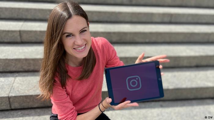 DW Meet the Germans host Rachel Stewart holds up an iPad with the Instagram symbol on it