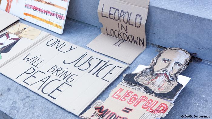 Activists' banners reading 'Leopold in Lockdown II' and 'Only justice will bring peace'