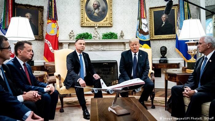 Presidents Donald Trump and Andrzej Duda, surrounded by other politicians, in the Oval Office