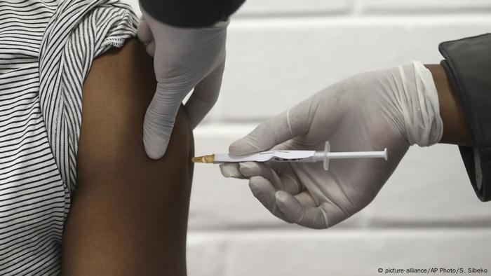 A health worker injects someone with a covid vaccine