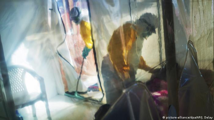 Un trabajador de salud ayuda a un paciente de ébola en el Congo.