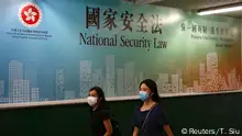 Women walk past a government-sponsored advertisement promoting the new national security law as a meeting on national security legislation takes place in in Hong Kong, China June 29, 2020. REUTERS/Tyrone Siu