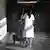 Woman cleaner in white jacket pushing cleaning cart along a hall